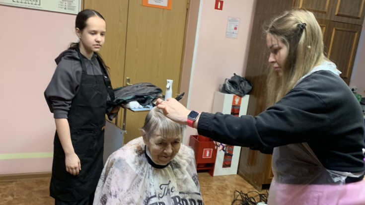 Парикмахер и его ученица подстригают одну женщину